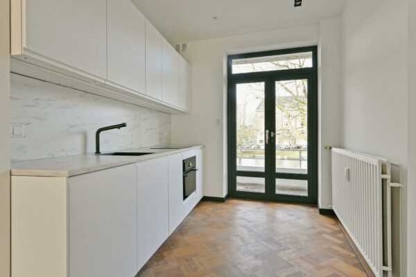Moderne witte keuken aan de Cornelis Dopperkade met uitzicht op het water door openslaande deuren.
